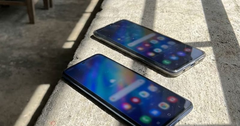 Two smartphones lying side by side on a concrete ledge in hard sunlight