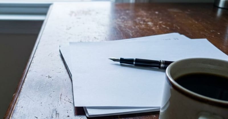 A printed contract and a pen on a dark wooden desk with a cup of coffee